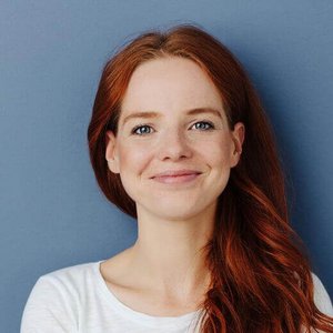 Eine Frau mit roten Haaren steht vor einer blauen Wand. Eine Frau mit roten Haaren steht vor einer blauen Wand.