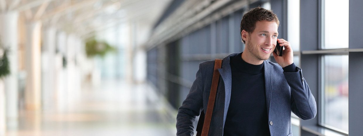 Ein Mann am Flughafen telefoniert mit seinem Smartphone.